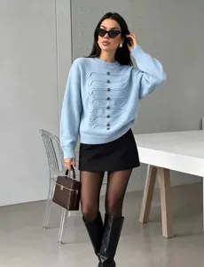 Detailansicht des hellblauen Strickpullovers mit Knopfdekoration und modernem Outfit.