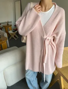 Gedetailleerd overzicht van roze gebreide wikkelvest met riem, textuur en elegante stijl.