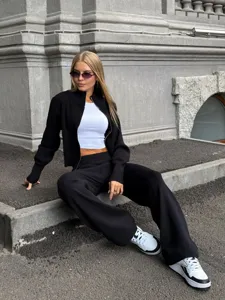 Λεπτομέρεια εξωτερικού street style με κομψή μαύρη πλεκτή ζακέτα και φαρδύ παντελόνι.