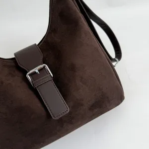 Detailed view of the dark brown suede shoulder bag featuring a chic leather buckle.