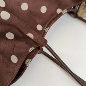 Detailed view of the brown polka dot pleated tote bag, soft fabric and leather handle.