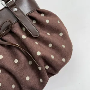 Brown polka dot shoulder bag with cute bow and leather strap, detailed close up view.