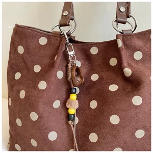 Brown polka dot tote bag detail view, large capacity shoulder bag with cute charm.