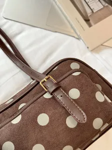 Détail de sac bandoulière marron à pois, sac oreiller stylé en suédine pour le bureau et quotidien.