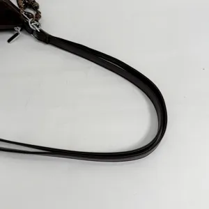 Detailed close-up view of the dark brown leather shoulder bag strap with fine hardware accents.