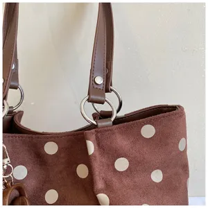 Brown polka dot tote bag detail view, soft suede fabric texture and metallic ring hardware.