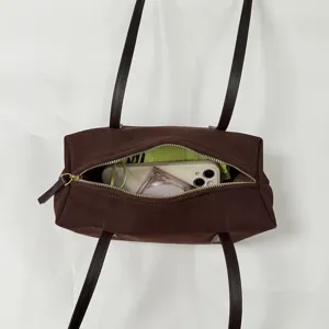Détail intérieur du sac à bandoulière en suédine marron, affichant un grand espace.