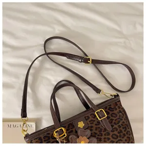 Leopard print tote bag with brown leather trim, gold hardware, and chic shoulder strap details.
