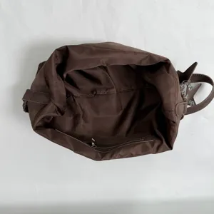 Detailansicht des braunen Innenfutters und Reißverschlussfachs einer geräumigen Schultertasche.