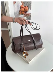 Detail shot of a vintage brown oil-wax leather baguette shoulder bag with chic metal buckle.