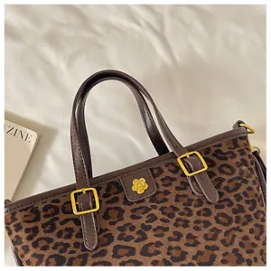 Leopard print tote bag detail showing luxury brown leather handle, gold buckle and flower accent.