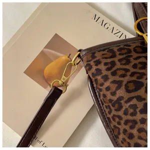 Leopard print tote bag detail featuring brown leather trim and luxury gold tone metal hardware.