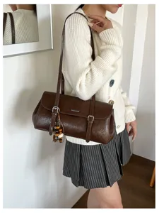 Vintage brown oil-wax leather baguette shoulder bag with beaded charm detail and metal buckle.