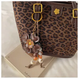 Close up of stylish leopard print tote bag featuring elegant flower charm and metal buckle detail.