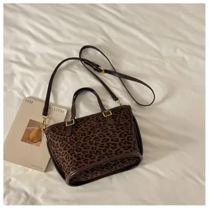 Detail view of the stylish leopard print tote bag with brown leather handles and chic crossbody strap.
