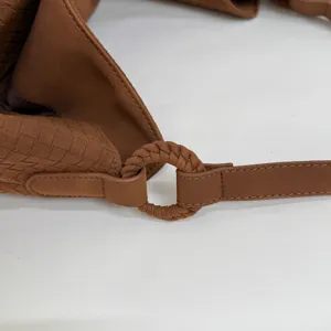 Braune gewebte Ledertasche Detail mit filigraner Intrecciato Textur und Ringbeschlag.
