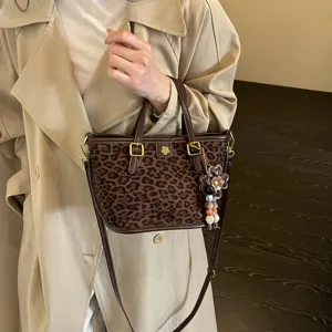 Detailed view of fashionable leopard print tote handbag with chic metal flower charm.