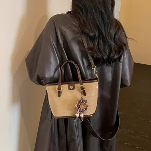 Detail shot of the brown suede leather tote bag showing its elegant floral charm and handles.