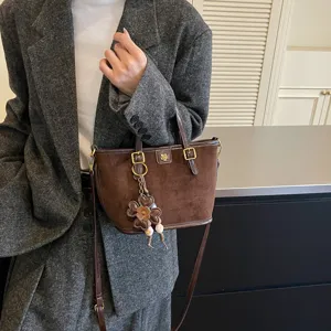 Brown suede tote bag detail, featuring exquisite flower charm and metal accent, elegant style.