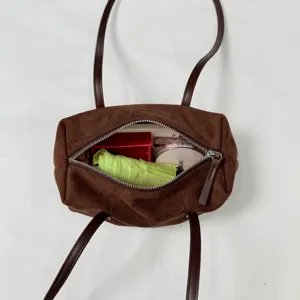 Detail view of brown suede pillow shoulder bag, showing spacious interior capacity and zipper.