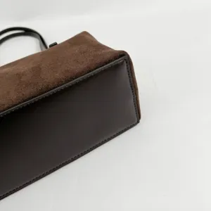 Brown suede and leather handbag detail shot showing premium texture and neat stitching.