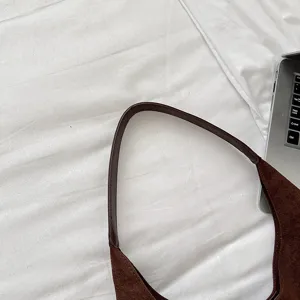 Brown suede hobo bag detail shot, vintage minimalist shoulder bag texture close-up for women.