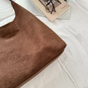 Close-up detail shot of brown vintage suede hobo shoulder bag texture and style.