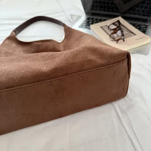 Detail shot of the brown suede hobo shoulder bag, showing fine texture and sleek curve.