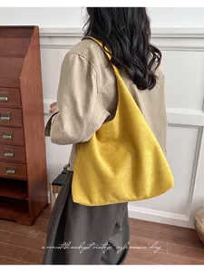 Detailed view of a vintage yellow suede hobo shoulder bag, minimalist everyday commute style.