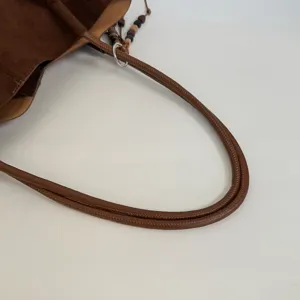 Braune Wildleder-Tragetasche Griffdetail, mit hochwertiger Ledertextur und Perlenanhänger.