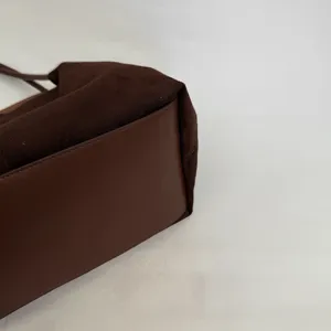 Detailaufnahme einer dunkelbraunen Wildleder und Ledertasche, schicke elegante Schultertasche Textur.