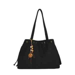 Schwarze Wildleder Shopper Schultertasche mit Kordelzug, Metallösen und Holzperlenanhänger.