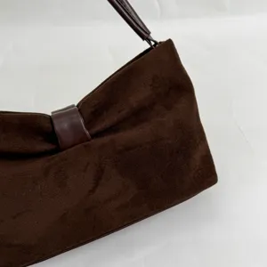 Close-up detail of brown suede shoulder handbag with smooth leather strap and elegant texture.