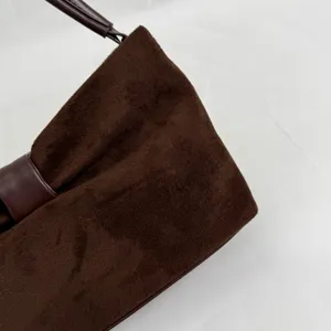 Brown suede handbag detail shot, featuring a stylish folded design and comfortable leather handle.