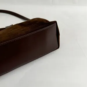 Close-up detail of dark brown suede shoulder handbag showing bottom texture and structure.