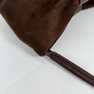 Brown suede handbag detail view, showing premium leather strap and soft textured material.