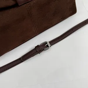 Close-up detail of the brown suede handbag strap, metal buckle, and neat stitching craft.