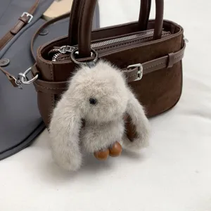 Detail view of the retro brown suede handbag featuring a cute plush bunny charm and metallic hardware.
