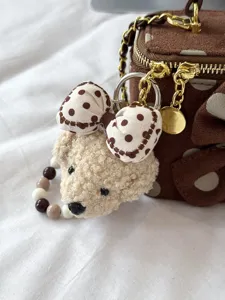 Polka dot box handbag detail view featuring cute plush bear bow keychain and gold chain strap.