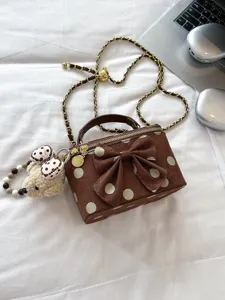 Brown polka dot handbag with bow and cute bear pendant, stylish crossbody chain bag detail.