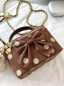 Close-up detail of the brown polka dot bow box bag with gold chain and soft suede texture.
