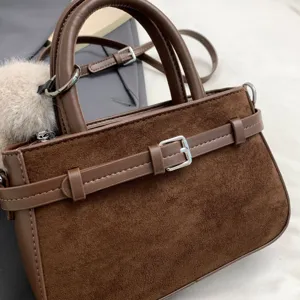 Close-up view of the retro brown suede handbag showcasing fine texture and chic metal buckle.