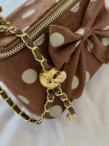 Brown velvet polka dot handbag detail showing a sweet bow and elegant gold chain strap.