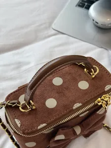 Brown suede polka dot vanity bag detail showing gold hardware, zipper, and elegant bow.