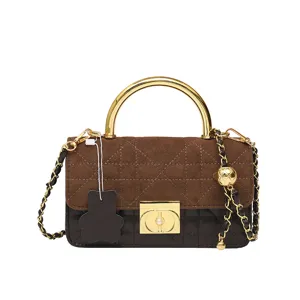 Nahaufnahme der braunen gesteppten Patchwork-Handtasche mit goldenem Griff und Kettendetails.