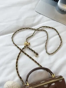 Brown polka dot box bag detail featuring leather woven chain strap and gold metal ball adjuster.