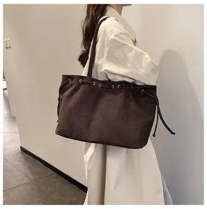 Detailansicht der braunen Wildleder-Tasche über der Schulter mit Metallösen und großem Stauraum.