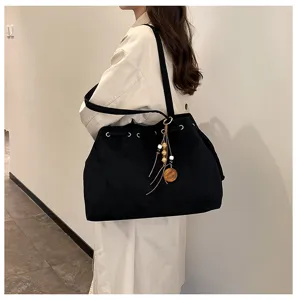 Detailansicht der schwarzen Tasche mit Kordelzug und elegantem schicken Quastenanhaenger.