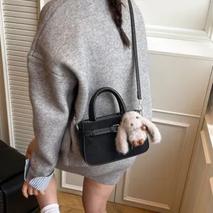 Stylish black suede handbag with top handle and furry rabbit pendant for women daily chic look.