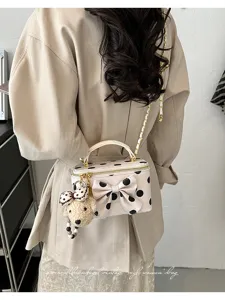 Detailed view of a sweet polka dot vanity bag with a bow and cute bear pendant on shoulder.